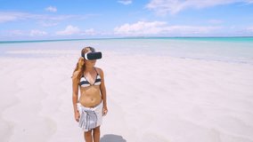 Aerial drone quad copter: Young tourist woman wearing virtual reality headset watching 360 travel video, imagination concept, looking around in headset tropical exotic beach paradise. 