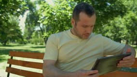 Positive man sitting in the park with the laptop