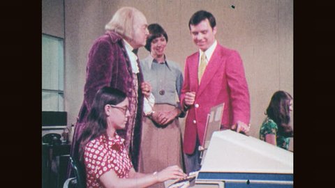 1970s: Woman sits and types at computer as people watch and talk. Fingers typing on keyboard. Thumb pushes buttons. Lit "Power On" button. Rolls of newsprint turn. Ben Franklin points in amazement.