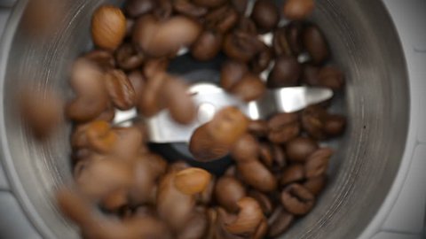 Roasted coffee beans poured into a coffee grinder. Close-up. 