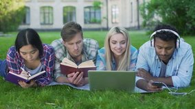Multi-ethnic men and women doing homework on grass on campus, higher education