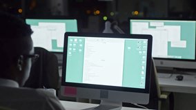 Panning shot of African businessman sitting in the office at night and writing report on computer - Powered by Shutterstock - Get 15% off with code: PIKWIZARD15