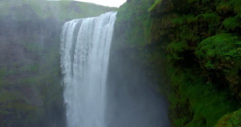 Large Waterfall in Green Canyon With Birds Flying Across Camera - Aerial footage of the Skógafoss Falls in Iceland