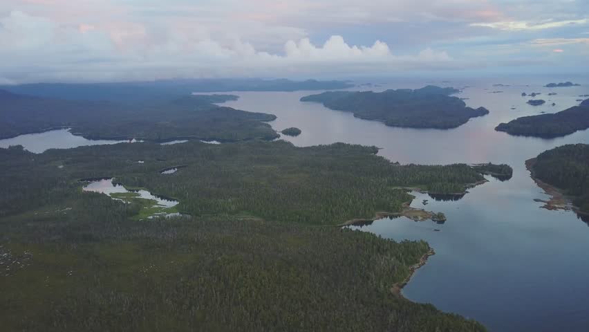 Dark Hazy Illuminating Sunset Over Alaskan Island Archipelago near Sitka Alaska. Sunset over the Pacific Ocean with Islands and green forest trees.