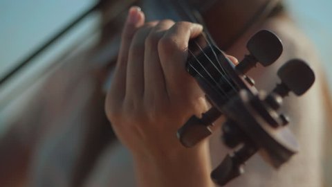Girl violinist playing the violin outdoors. Green leaves backgound. Close up. Musician playing. Slow motion.