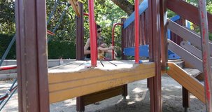 4k video. Three years old blonde child with woman playing climbing and descending sliding down metal bar in outdoor playground, in public park of Madrid city (Spain)
