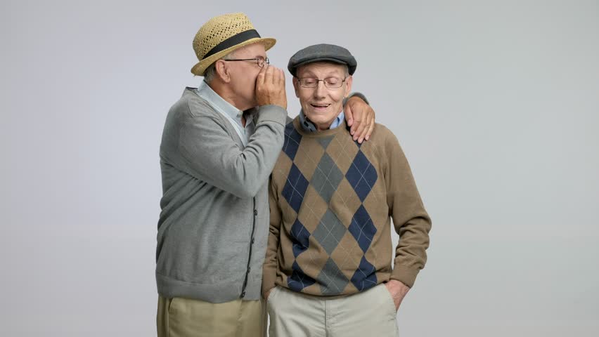 Senior whispering something funny to another senior isolated on gray background. | Shutterstock HD Video #29193571