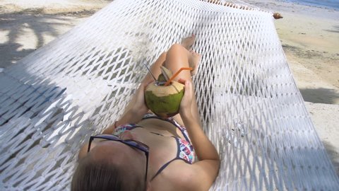 Young Woman Swinging in Hammock with Coconut. Vacation in Paradise