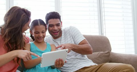 Happy family sitting on sofa and using digital tablet in living room