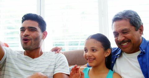 Family watching television and cheering in living room