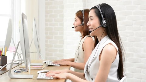 Happy beautiful Asian telemarketing customer service agent team working in the office, call center job concept