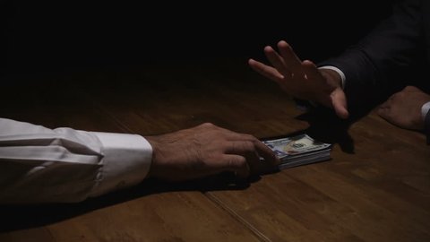 Businessman rejecting money offered by his partner in the dark - anti bribery concept