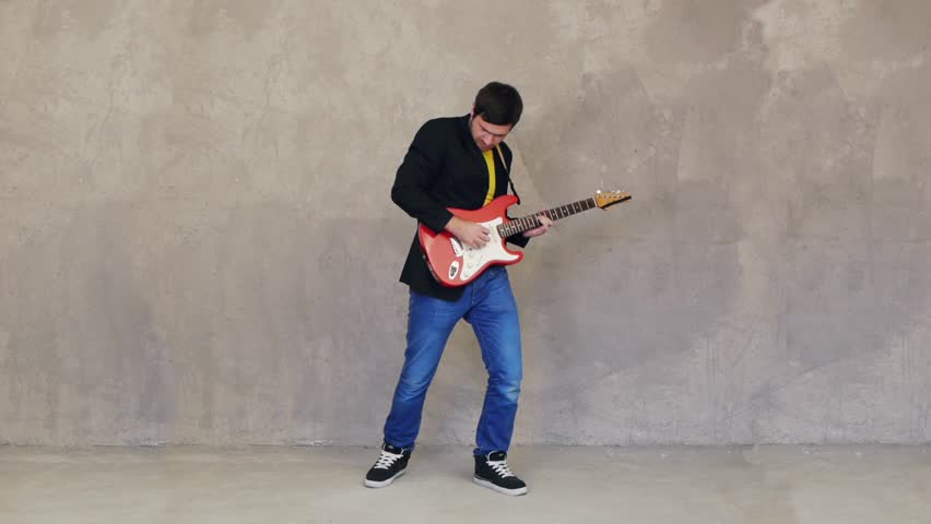 Guitarist standing and playing solo on guitar in studio