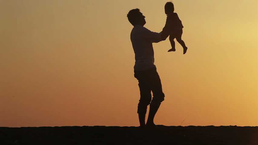 Silhouette of father turns his son over sunset