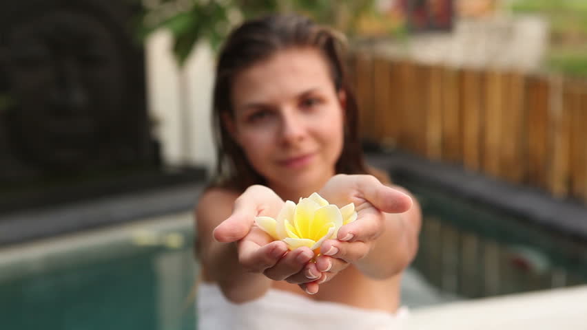 Attractive woman holding flower and smelling it