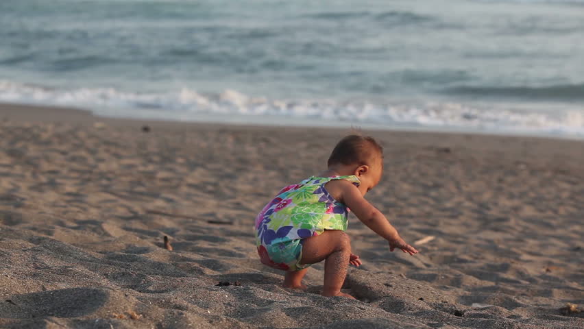 Adorable toddler playing with sand at the beach