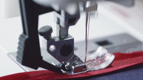 Super slow motion of a professional sewing machine stitching red braid with red thread an couture fabric, The seamstress sews a high fashion outfit. concept of industry, tradition, fashion