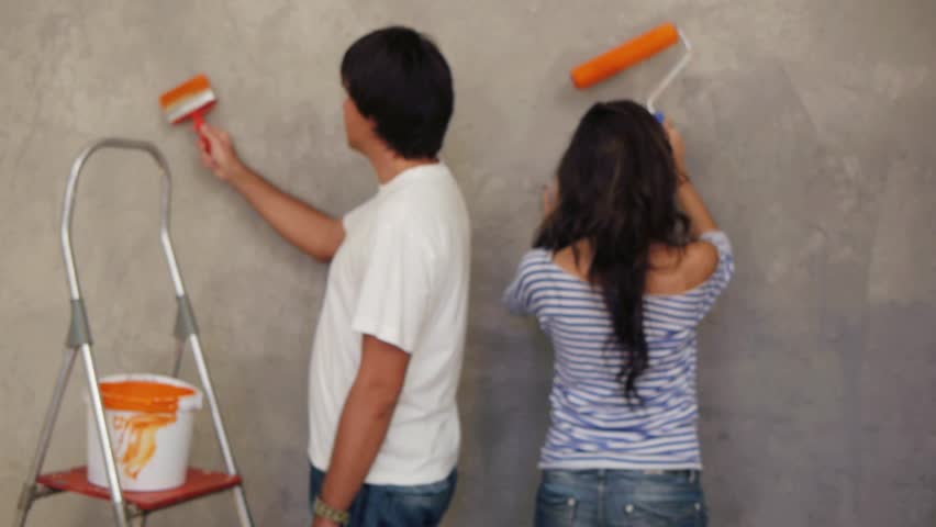 Attractive couple painting wall together