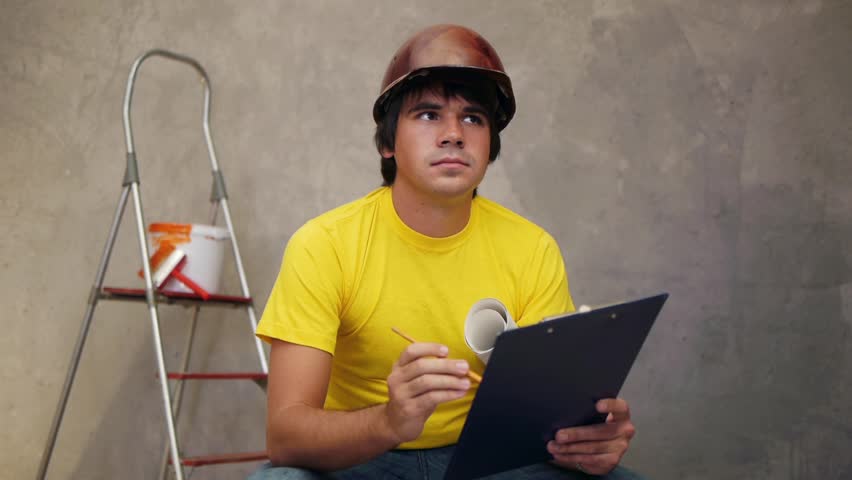 Attractive architector in helmet writing notes