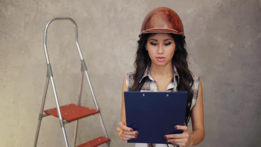 Smiling female worker writing something on clipboard