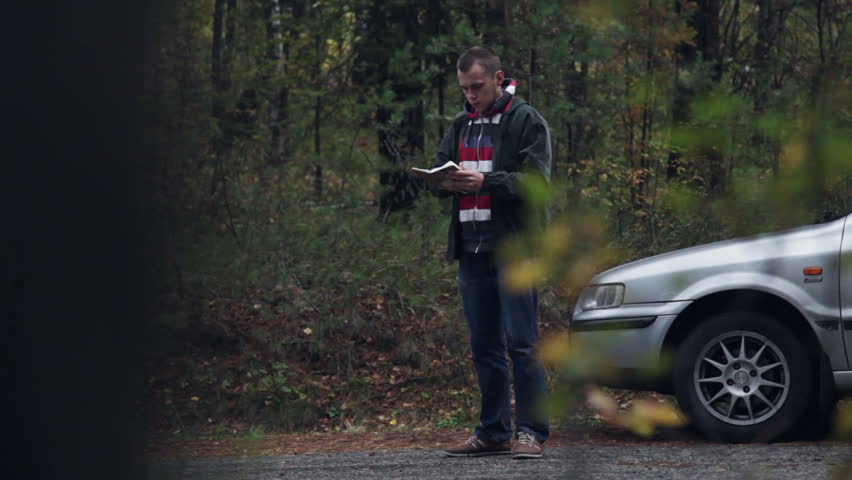 Man standing near car and reading his notes