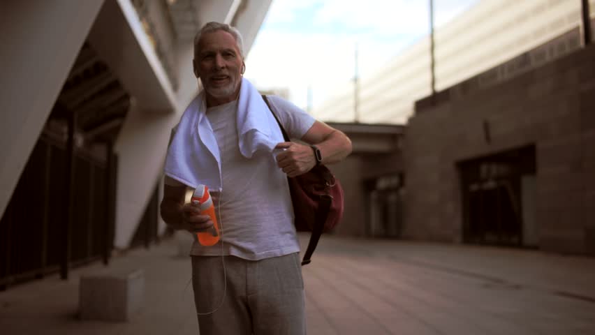 Smiling senior man walking after sport exercises