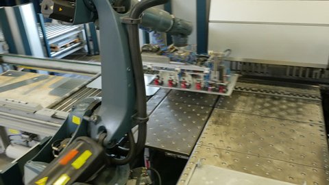 Fully automatic panel bending center in metal factory for shaping steel with robot arm moving around