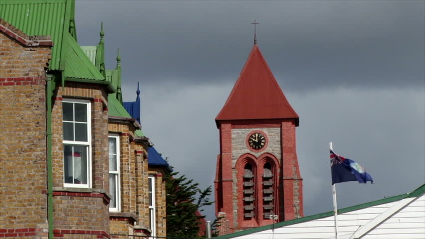 Details of upper floor of very British looking houses on Philomel Street, Port Stanley, Falkland Islands.The Falkland flag flies in front. And Christ Church Cathedral is in the background