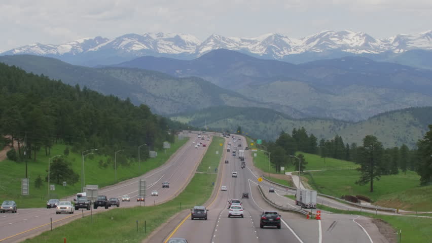 Busy traffic on Interstate Highway leading out Denver and into the rugged snowcapped Rocky Mountains of Colorado.  