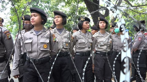 JAKARTA, INDONESIA - 1 MAY 2017: Female riot police officers behind barbed wire fence at May Day protest rally in Jakarta, Indonesia