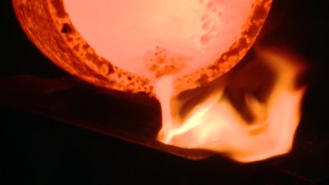 HD. An operator takes a crucible filled with molten silver and empties it into a mold. The liquid falls boiling inside the mold where it will cool
