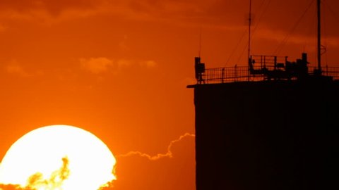 Bright sun appear from clouds behind dark silhouette of skyscraper Video de stock