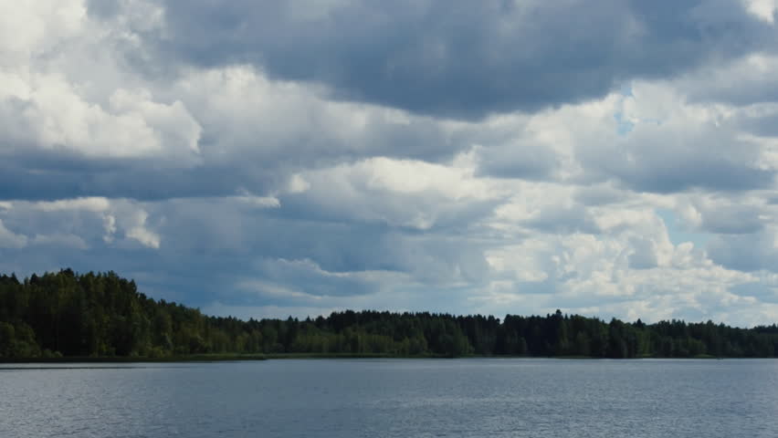 Spectacularly swirling clouds before thunder storm. Shore of forest lake that summer day. Timelapse, fisherman on boat in frame
