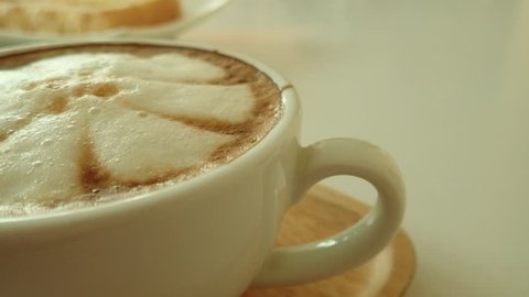 SLOW MOTION of Latte coffee with cream foam on top and perspective view closeup background