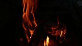 Closeup of burning bright fire in fireplace in darkness. Christmas (Xmas) or New Year shiny blurry bokeh video background. Real time full hd video footage.