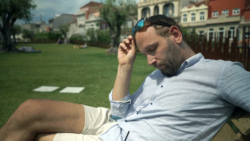 Sad, unhappy man sitting in garden in cafe
