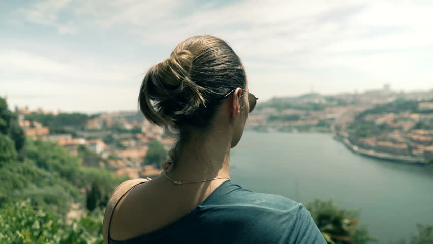 Young woman admire view of Porto standing on terrace in garden
