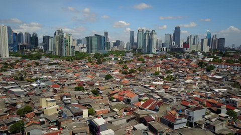 JAKARTA, INDONESIA - APRIL 2017: Flying backwards over blue mosque and residential area, with modern skyline of Jakarta as backdrop