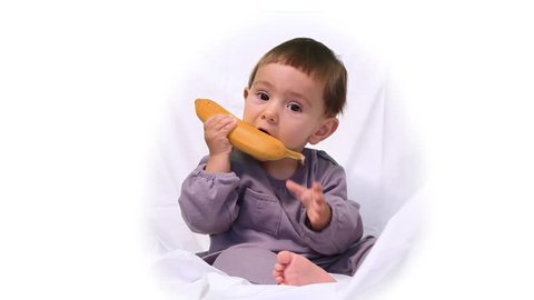 Cute little baby girl plays with banana.
