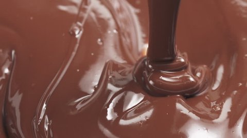 Slow motion pouring premium milk melted chocolate from big spoon