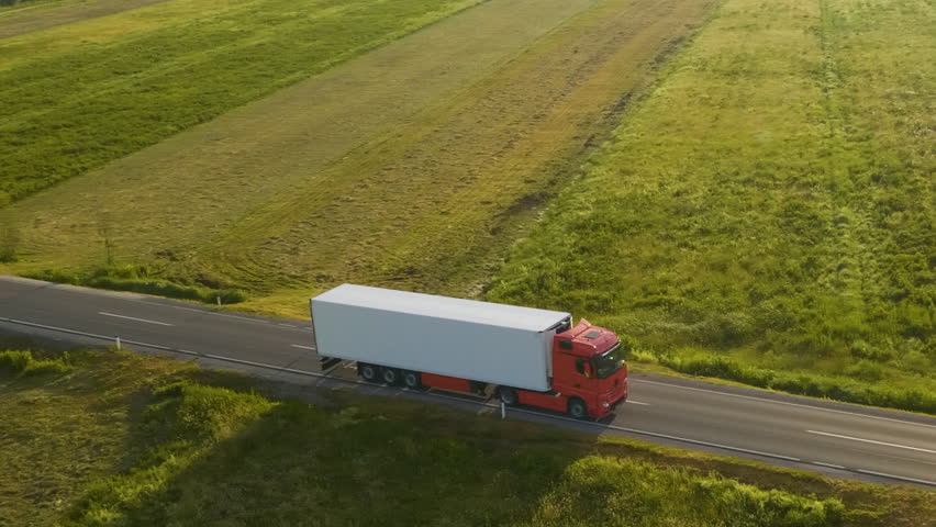 Aerial shot of a truck on the road in beautiful countryside in the summer.