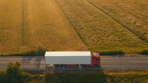 Aerial side shot of a truck on the road in beautiful countryside in the sunset light.