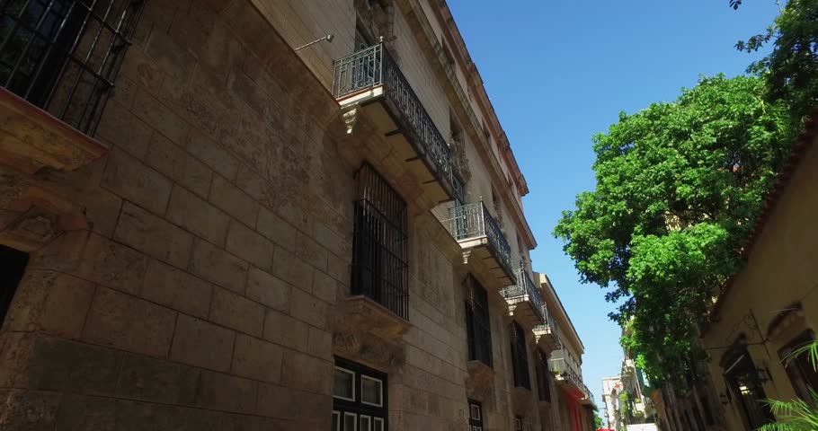 A tracking dolly shot looking up at the balconies on buildings on a typical narrow street in Havana
