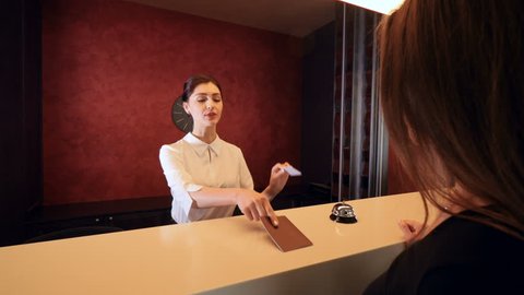 Girl approaching hotel reception to take the key.