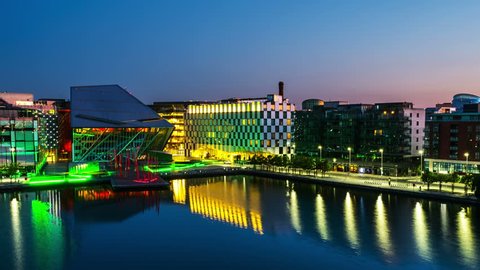 Dublin, Ireland. Aerial view of Grand Canal docks in Dublin, Ireland at sunrise. Empty streets and illuminated modern buildings, colorful clear sky. Time-lapse from night to day. Zoom in