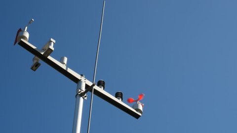 The anemometer in the sun's rays measures the wind speed. The meteo station on the blue sky background.