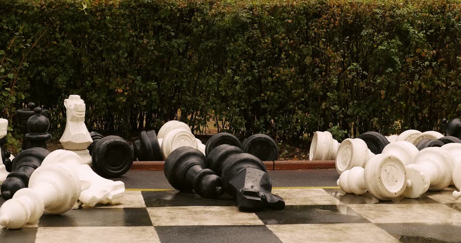 Gigantic chessboard and chess pieces supradimensional in green park on a rainy day near kids playground