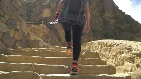Woman Walking up Incan Steps.  Hiking up ancient rock steps in the ruins of Ollantaytambo Peru.  Slow Motion
