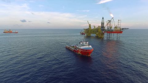 KELANTAN, MALAYSIA - JULY 18, 2017: Supply vessel with offshore jack-up drilling rig and gas production platform. An FSO (Floating, Storage and Offloading) vessel also can be seen in this footage.