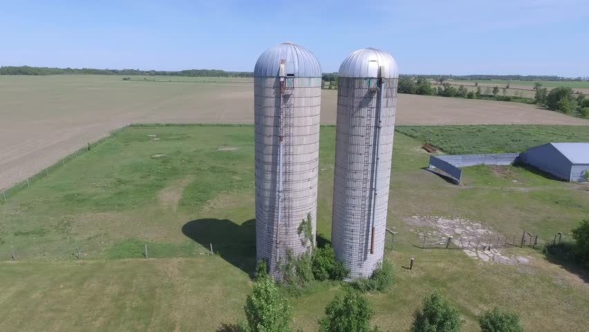aerial farm side flight reveals horses behind silos